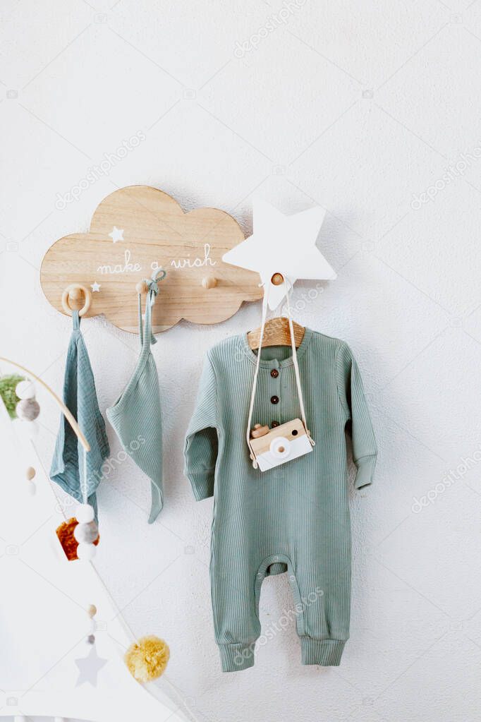 Clothes for newborns and wooden toys hang on the wall, Nordic style, light background, baby concept
