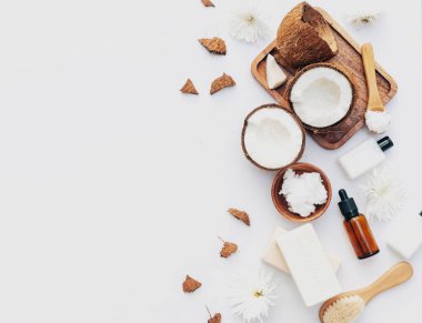 Beyaz arka planda hindistan cevizi parçaları ve vücut bakım ürünleriyle organik sağlıklı hindistan cevizi ezmesi.