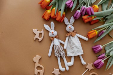 Kahverengi arka planda tavşan oyuncakları olan taze bahar laleleri. Mutlu Paskalya bayramı kartları. Bebek oyuncakları. 