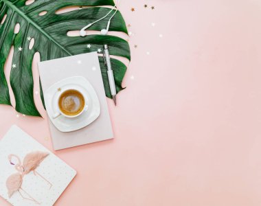 Üst düzey kadın ofis masası, kahve fincanı olan çalışma alanı, pembe arka planda canavar yaprağı.. 