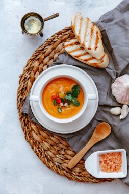 Taze domates çorbası ve ekmek çubuğu gri masada, yaz yemeği İspanyol gazpacho, üst manzara, düz kopya alanı 