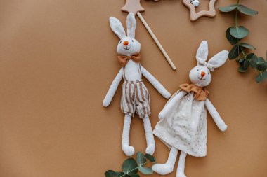 Kahverengi arka planda tahta oyuncakları olan iki tavşan. Üst manzara, düz uzanma 