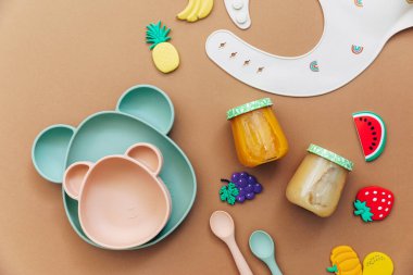 Işık arka planında parlak silikon bulaşık takımı. Bebeğe hizmet etmek, ilk beslenme konsepti. Düz konum, boşluk kopyala, üst görünüm