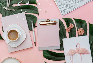 Kadınsı düz yatak, blogcular için tropikal pembe arka plan üzerine pano, pastel pembeli modern ofis masası, kahve fincanı ve kırtasiye malzemesi..