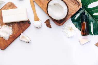 Beyaz arka planda hindistan cevizi parçaları ve vücut bakım ürünleriyle taze organik hindistan cevizi yağı.