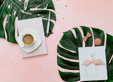 Üst düzey kadın ofis masası, kahve fincanı olan çalışma alanı, pembe arka planda canavar yaprağı.. 