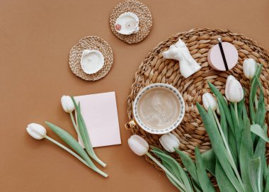 Bahar kompozisyonu. Beyaz laleler, kahve fincanı, kahverengi arka planda mum. Anneler Günü, 8 Mart. Boş tebrik kartı. Düz Yat 