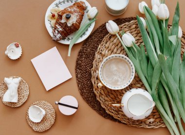 Bahar kompozisyonu. Beyaz laleler, kahve fincanı, kahverengi arka planda mum. Anneler Günü, 8 Mart. Boş tebrik kartı. Düz Yat 