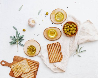 Üst görünüm organik zeytinyağı, zeytinyağı, taze tost ekmeği ve beyaz zemin üzerinde zeytin dalı, yazı için yer, düz uzanma