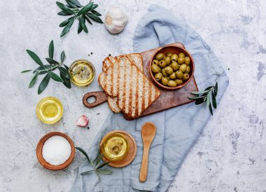 Yeşil zeytin, zeytinyağı ve ciabatta ekmeği. Üst görünüm düzlüğü kopyalama alanı ile yatıyordu