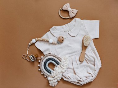 Bebek partisi konsepti. Yeni doğmuş bebek kıyafetleri, laleler ve kahverengi arka planda ahşap oyuncaklar.