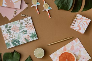 Düz uzanmış tropik orman canavarı yaprakları, kağıt defter, yaz arkaplanı. Üst düzey kadın günlüğü ve kırtasiye malzemeleri ofis masasında.