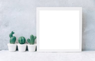 Minimum beyaz çerçeve ve seramik kaktüsler raflarda ya da masalarda saksılarda. Beyaz raf ve duvar. 