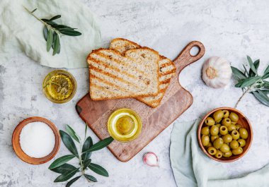 Üst görünüm zeytinyağı, zeytinyağı, kızarmış ekmek ve yapraklar beyaz arka planda, yazı için boşluk