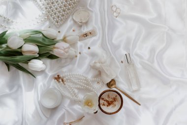 Kadın bahar geçmişi, kahve fincanı, mum, laleler ve ipek arka planda kadın aksesuarı olan bir yaşam kompozisyonu. Kadınlar bayramı. Anneler Günü. Kadınlar Günü.