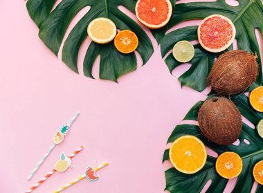 Pembe arka planda canavar yaprakları ve hindistan cevizi. Düz konum, üst görünüm, kopyalama alanı. Yaz tropik arka plan