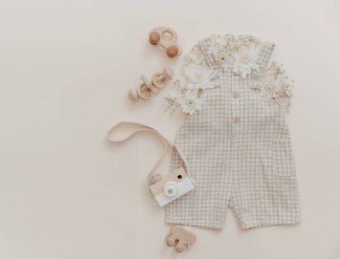 Çiçekli yumuşak bebek pantolonu. Moda yeni doğmuş, bohem tarzı, doğal bej renkler. Düz yerde, üst tarafta. Doğal tekstil, pastel arkaplan. 