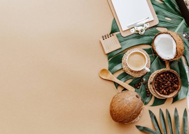Kadın aksesuarları, Ratan çantası, hasır şapka, canavarlar, kahve fincanı ve kahverengi arka planda boş bir not. Düz yatış, üst görünüm