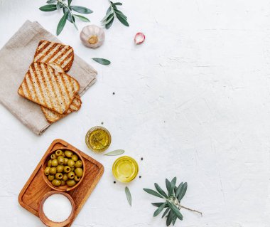 Yeşil zeytin, zeytinyağı ve ciabatta ekmeği. Üst görünüm düzlüğü kopyalama alanı ile yatıyordu