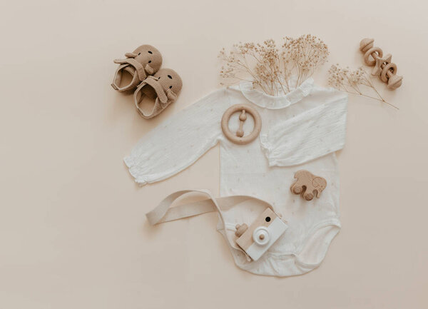 Детские аксессуары из натурального материала. Деревянные игрушки, одежда и обувь на бежевом фоне. Детская мода Чехии.