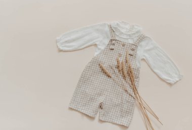 Bebek doğal aksesuar konsepti. Tahta oyuncaklar, kıyafetler ve bej arka planda ayakkabılar. Bohem bebek modası.