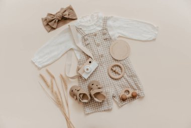 Vücut kıyafetli doğal keten bebek şamatası. Bej arka planda çevre dostu yeni doğmuş kıyafetler, bahar ya da yaz için bebek kıyafetleri ve aksesuarlar. Bohem stili