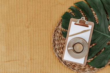 Kahveli ve yeşil yapraklı düz bir pano. Metin için yeri olan boş bir belge sahibi. Ofis kırtasiyesi. Blogger konsepti. Ofis çalışma alanı. Bağımsız 