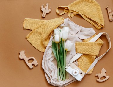 Beyaz arka planda yazlık bebek kıyafetleri, yeni doğan moda konsepti laleli tarafsız vücut giysisi ve çevre dostu oyuncaklar. Üst görünüm 