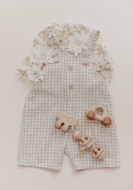 Çiçekli yumuşak bebek pantolonu. Moda yeni doğmuş, bohem tarzı, doğal bej renkler. Düz yerde, üst tarafta. Doğal tekstil, pastel arkaplan. 