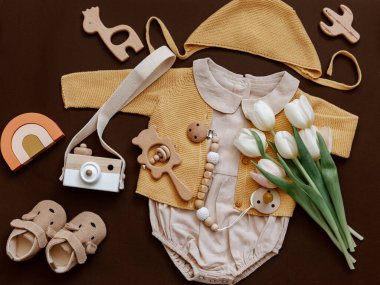 Çevre dostu bebek aksesuarları ve laleleri olan düz bir bebek tulumu. Yeni doğan moda kavramı