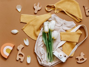 Beyaz arka planda yazlık bebek kıyafetleri, yeni doğan moda konsepti laleli tarafsız vücut giysisi ve çevre dostu oyuncaklar. Üst görünüm 