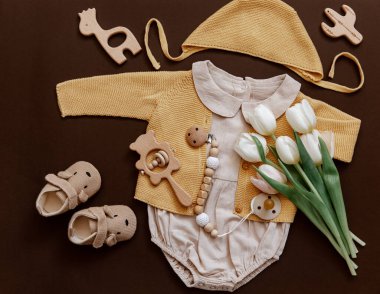 Çevre dostu bebek aksesuarları ve laleleri olan düz bir bebek tulumu. Yeni doğan moda kavramı