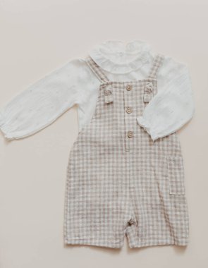 Vücut kıyafetli doğal keten bebek şamatası. Bej arka planda çevre dostu yeni doğmuş kıyafetler, bahar ya da yaz için bebek kıyafetleri ve aksesuarlar. Bohem stili