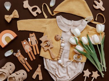 Çevre dostu bebek aksesuarları ve laleleri olan düz bir bebek tulumu. Yeni doğan moda kavramı