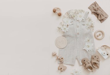 Çiçekli yumuşak bebek pantolonu. Moda yeni doğmuş, bohem tarzı, doğal bej renkler. Düz yerde, üst tarafta. Doğal tekstil, pastel arkaplan. 