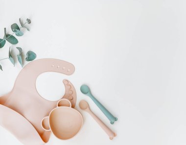 Bebek beslenme aksesuarları. Silikon önlük, bulaşık takımı. Düz konum, üst görünüm, kopyalama alanı.