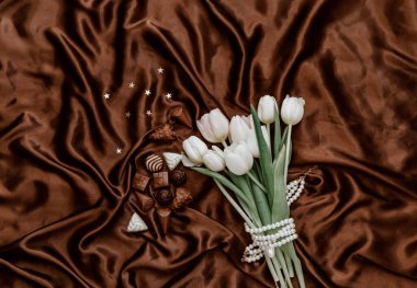 Düz beyaz laleler ve ipek arka planda çikolata mumu vardı. Üst görünüm 