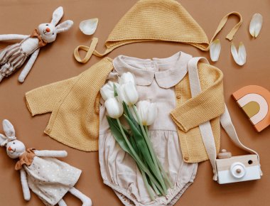 Beyaz arka planda yazlık bebek kıyafetleri, yeni doğan moda konsepti laleli tarafsız vücut giysisi ve çevre dostu oyuncaklar. Üst görünüm 