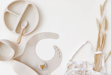 Bebek için düz bej silikon bulaşık takımı. Çocuğa ilk beslenme konseptini vermek. Boşluğu kopyala, üst görünüm