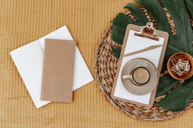 Kahveli ve yeşil yapraklı düz bir pano. Metin için yeri olan boş bir belge sahibi. Ofis kırtasiyesi. Blogger konsepti. Ofis çalışma alanı. Bağımsız 