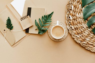 Kahve fincanı, takvim, kahverengi arka planda yeşil yapraklarla yatıyordu. Serbest İşyeri, yapılacaklar listesi, ofis masası, planlama konsepti 