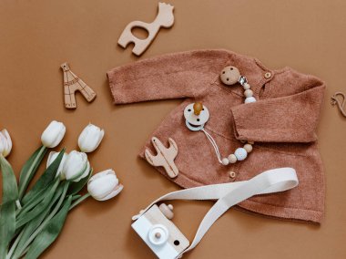 Laleli düz kompozisyon, kız örgü ceket ve ahşap kamera. Yeni doğan kıyafetleri, bebek eşyaları, bebek partisi. Üst manzara, düz uzanma 