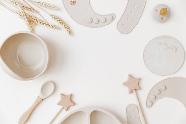 Tarafsız arka planda Şirin bebek plakası ve silikon önlüğü vardı. Üst manzara, düz yatış, ilk yemek servisi yapan bebek.