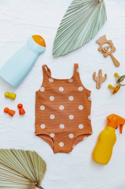 Bebek mayosu, plaj aksesuarları ve güneş kremi. Çocuklar için güneş losyonu. Ultraviyole koruma ürünü kavramı, yaz çocukları kozmetik ürünleri.