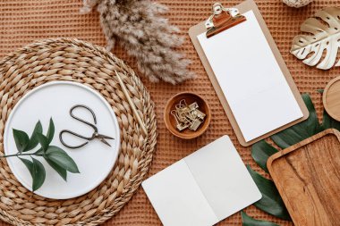 Boş kağıt pano modeli, canavar yaprağı ve ofis malzemeleriyle düz bir ofis masası. Modern kadın çalışma alanı kavramı.