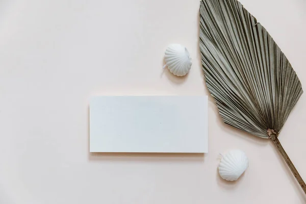 Summer stationery minimal mock-up. Blank card, palm leaves, beige textured table background. Wedding mock up. Flat lay, top view