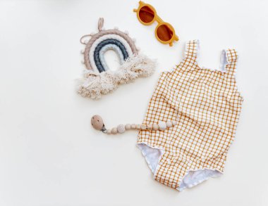 Summer kid's vacation concept - swimsuit with  and sunglasses on neutral beige background, minimal holiday  fashion baby. Top view, flat lay 