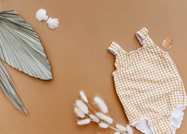 Yaz tatili konsepti, kahverengi arka planda aksesuarları olan yaz çocuğu mayosu. Küçük kızlar yaz kıyafetleri giyer..