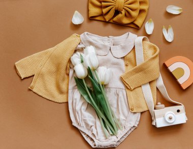 Beyaz arka planda yazlık bebek kıyafetleri, yeni doğan moda konsepti laleli tarafsız vücut giysisi ve çevre dostu oyuncaklar. Üst görünüm 