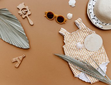 Yaz tatili konsepti, kahverengi arka planda aksesuarları olan yaz çocuğu mayosu. Küçük kızlar yaz kıyafetleri giyer..